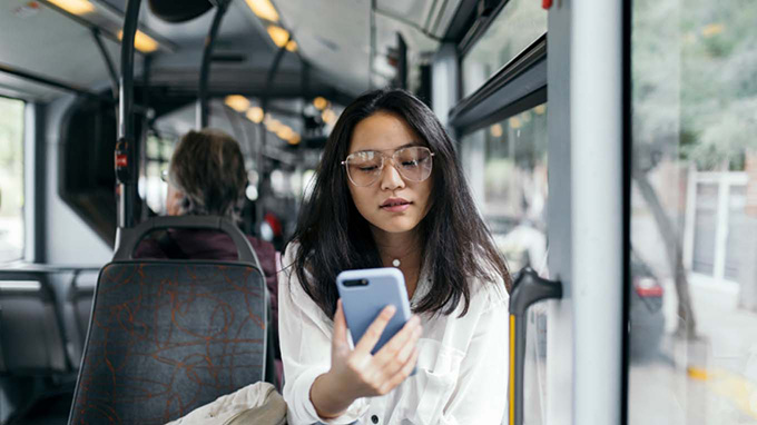 A woman sitting in a bus stares at her phone.